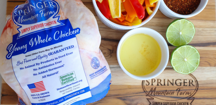 Springer Mountain Farms Young Whole Chicken on a wooden cutting board with fresh carrots, celery, onion, and herbs — the perfect ingredients for cooking healthy, budget-friendly meals with whole chicken.