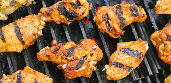 Chicken wings sizzling on a charcoal grill with perfect dark grill marks, capturing the essence of backyard BBQ.