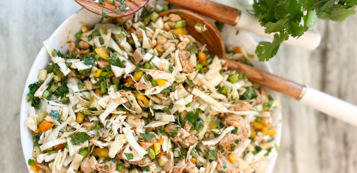 Colorful Asian chopped chicken salad with cabbage, carrots, edamame, and herbs in a white bowl – healthy summer chicken recipe with sesame dressing