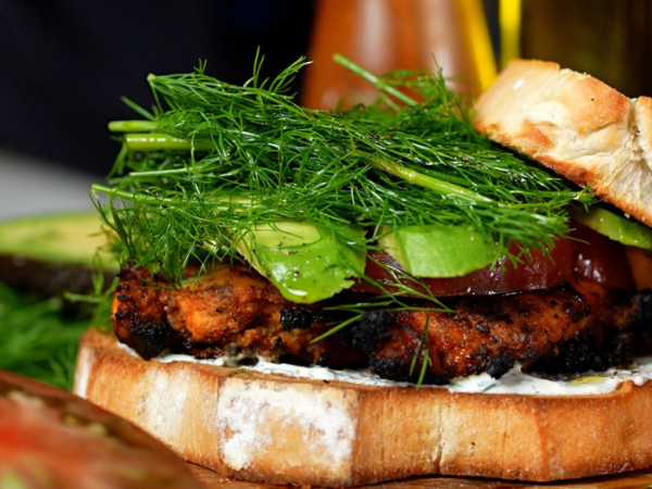 Grilled chicken bacon ranch sandwich stacked with juicy chicken breast, crispy bacon, avocado, fresh dill, heirloom tomato, and creamy ranch dressing on toasted white bread.