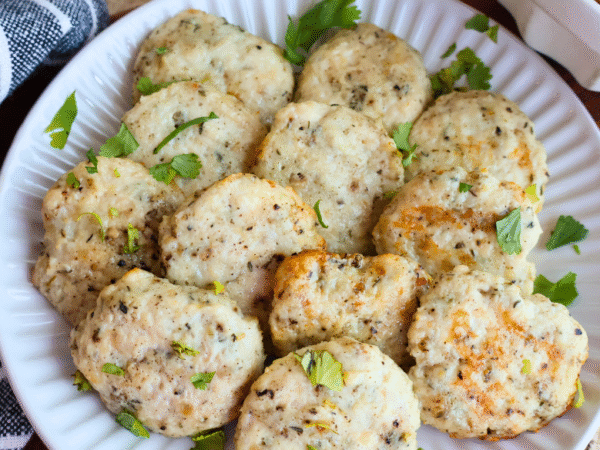Homemade chicken breakfast sausage patties on a white plate, garnished with fresh parsley. Juicy, golden-brown, and perfectly seasoned, these protein-packed chicken sausages make a healthy, flavorful breakfast option made with Springer Mountain Farms Simply Superior Chickenā¢.