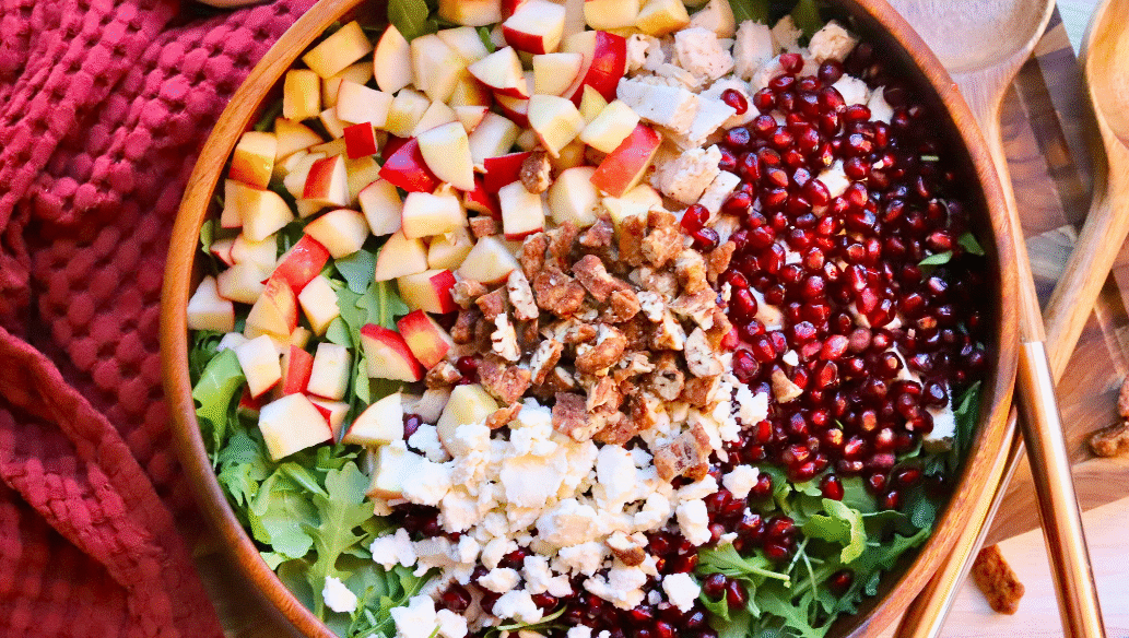 Healthy fall salad with Springer Mountain Farms Herb Poached Chicken, fresh apples, pomegranate seeds, candied pecans, and feta over arugula — easy seasonal recipe.