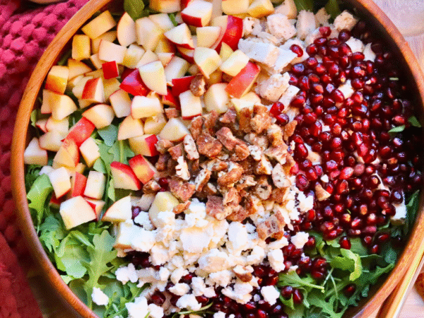 Healthy fall salad with Springer Mountain Farms Herb Poached Chicken, fresh apples, pomegranate seeds, candied pecans, and feta over arugula — easy seasonal recipe.