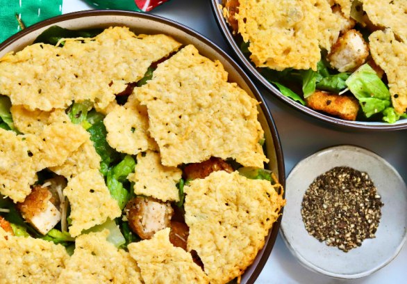 Crispy chicken Caesar salad topped with crunchy parmesan crisps and golden potatoes, served with fresh romaine and cracked black pepper.