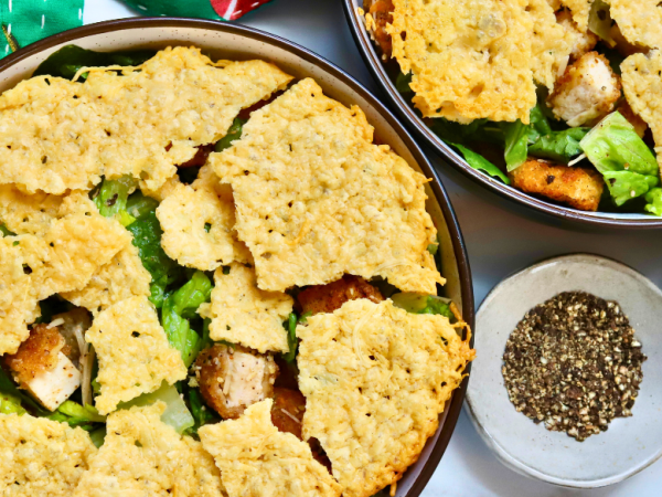 Crispy chicken Caesar salad topped with crunchy parmesan crisps and golden potatoes, served with fresh romaine and cracked black pepper.