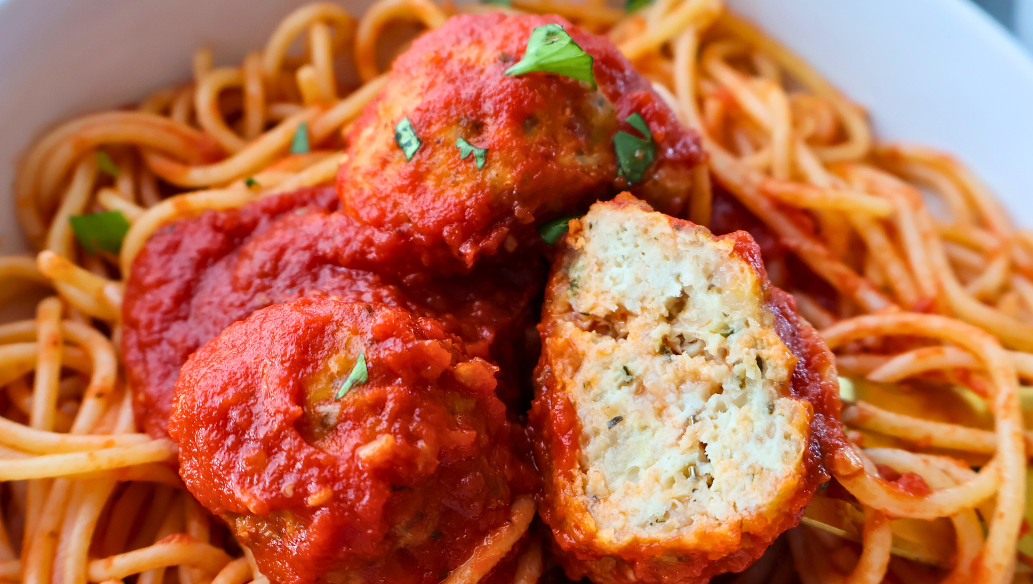 Close-up of spaghetti topped with juicy Italian chicken meatballs in marinara sauce, garnished with fresh parsley – perfect freezer-friendly dinner idea.