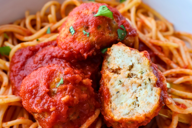 Close-up of spaghetti topped with juicy Italian chicken meatballs in marinara sauce, garnished with fresh parsley – perfect freezer-friendly dinner idea.