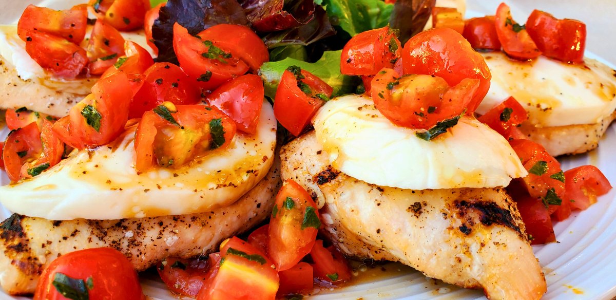 Grilled Springer Mountain Farms 4 oz boneless skinless chicken breasts topped with fresh mozzarella, cherry tomatoes, basil, and balsamic glaze for a healthy Caprese chicken recipe perfect for summer grilling.