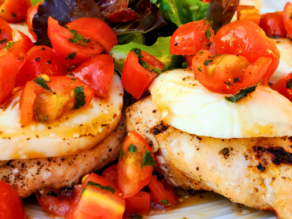 Grilled Springer Mountain Farms 4 oz boneless skinless chicken breasts topped with fresh mozzarella, cherry tomatoes, basil, and balsamic glaze for a healthy Caprese chicken recipe perfect for summer grilling.