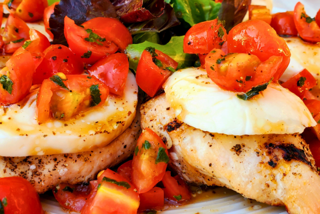 Grilled Springer Mountain Farms 4 oz boneless skinless chicken breasts topped with fresh mozzarella, cherry tomatoes, basil, and balsamic glaze for a healthy Caprese chicken recipe perfect for summer grilling.