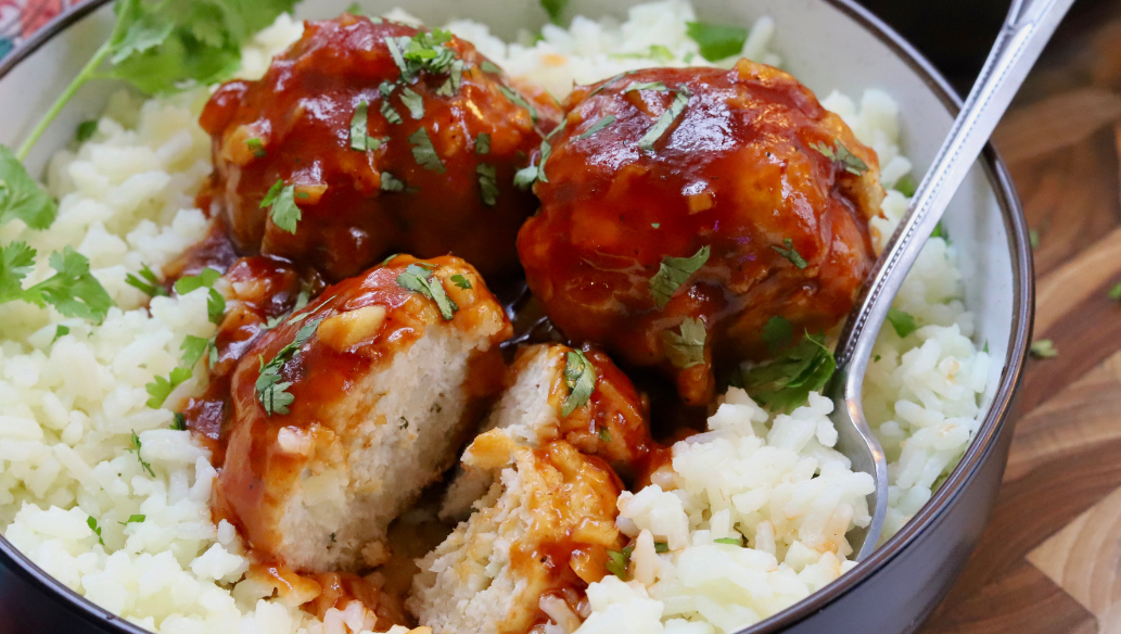 Sweet and sour chicken meatballs glazed in sticky sauce, served over white rice and garnished with fresh cilantro.