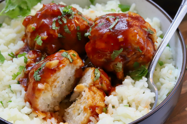 Sweet and sour chicken meatballs glazed in sticky sauce, served over white rice and garnished with fresh cilantro.