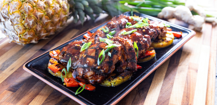 Grilled Huli Huli Springer Mountain Farms chicken thighs glazed with sweet pineapple-soy sauce and served on grilled pineapple and red peppers