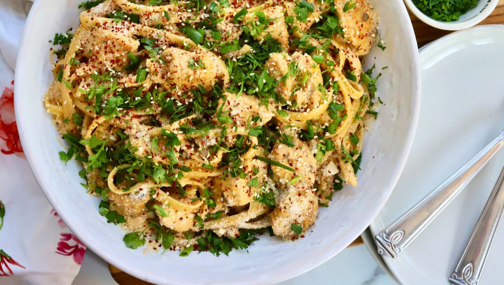 Korean Chicken Fettuccini Noodles topped with sesame seeds, cilantro, red pepper flakes, and green onions in a white bowl – spicy creamy Asian fusion pasta with chicken breast.