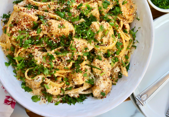 Korean Chicken Fettuccini Noodles topped with sesame seeds, cilantro, red pepper flakes, and green onions in a white bowl – spicy creamy Asian fusion pasta with chicken breast.
