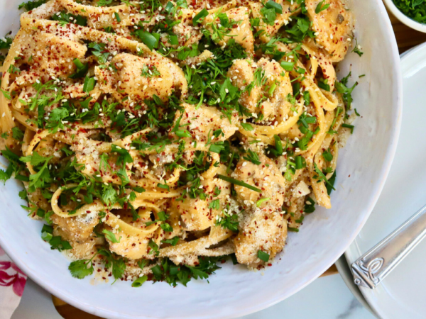 Korean Chicken Fettuccini Noodles topped with sesame seeds, cilantro, red pepper flakes, and green onions in a white bowl – spicy creamy Asian fusion pasta with chicken breast.