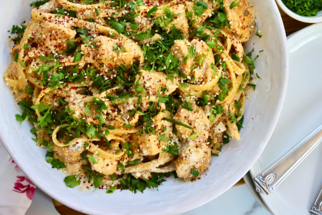 Korean Chicken Fettuccini Noodles topped with sesame seeds, cilantro, red pepper flakes, and green onions in a white bowl – spicy creamy Asian fusion pasta with chicken breast.