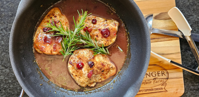Pan-seared chicken breasts in cranberry orange sauce with fresh rosemary.