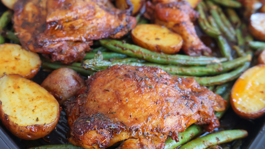 Sheet pan roasted chicken thighs with crispy baby potatoes and seasoned green beans, baked to perfection for an easy one-pan dinner"