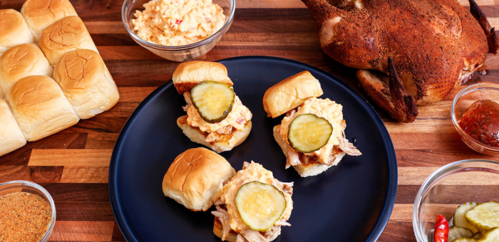 Smoked pulled Springer Mountain Farms chicken sliders topped with creamy pimento cheese and pickles, served on sweet Hawaiian rolls with sides
