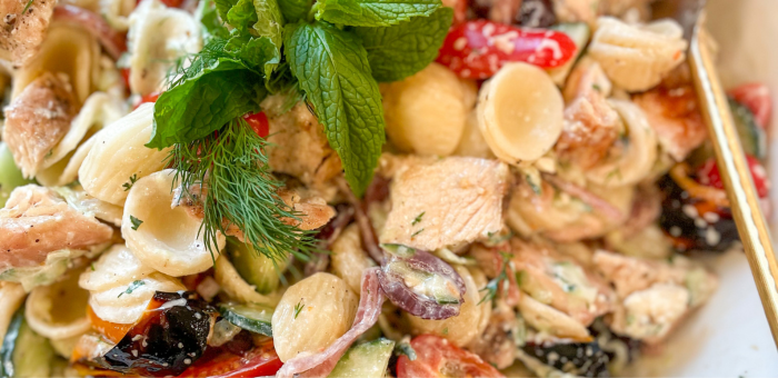 Colorful tzatziki chicken pasta salad with orecchiette pasta, grilled chicken chunks, cucumbers, tomatoes, olives, red onion, and fresh herbs like dill and mint.