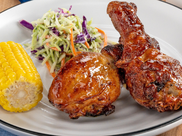 Air fryer chicken drumsticks glazed with peach BBQ sauce served with coleslaw and corn on the cob