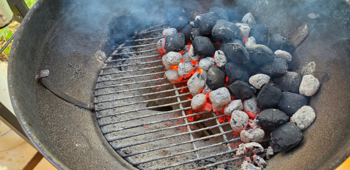 charcoal grill set up with coals on one side for two-zone heat grilling