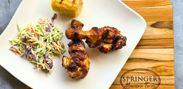 fully cooked grilled chicken drumsticks with coleslaw and corn