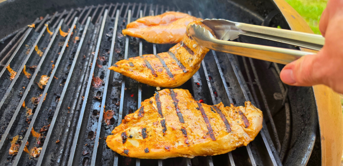Flipping grilled chicken breast showing grill marks