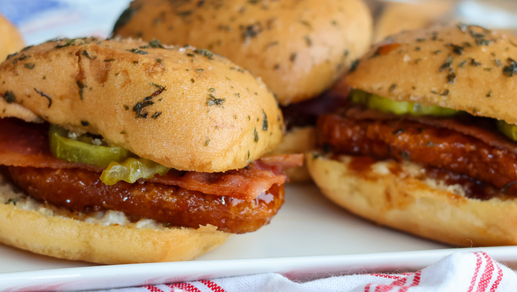 Hot honey chicken sliders with bacon, pickles and ranch made with Springer Mountain Farms fully cooked gluten free breaded chicken strip fritters.