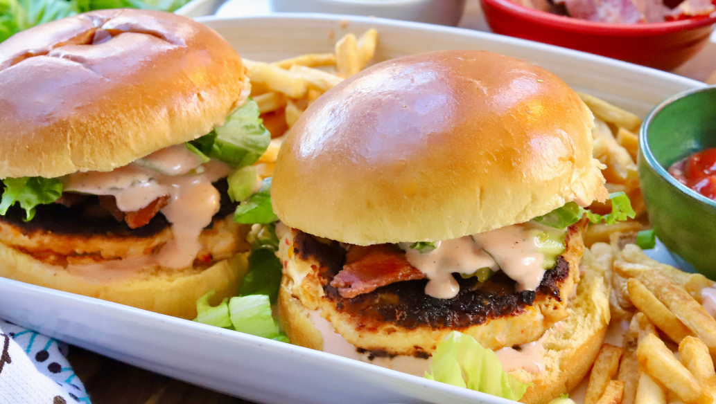 Juicy pimento cheese chicken burgers with bacon, lettuce, and spicy ranch on brioche buns served with fries