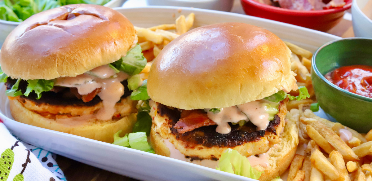 Juicy pimento cheese chicken burgers with bacon, lettuce, and spicy ranch on brioche buns served with fries