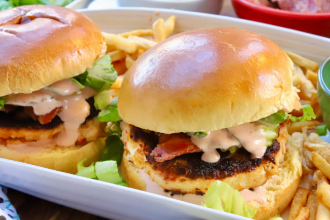 Juicy pimento cheese chicken burgers with bacon, lettuce, and spicy ranch on brioche buns served with fries