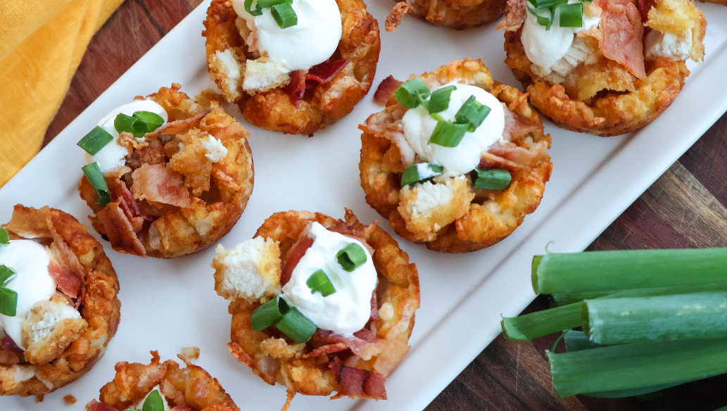 Loaded chicken bacon tater tot cups topped with sour cream and green onions