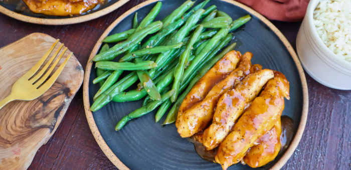 Sweet chili skillet chicken tenders served with sautéed green beans and a side of white rice on a plate.